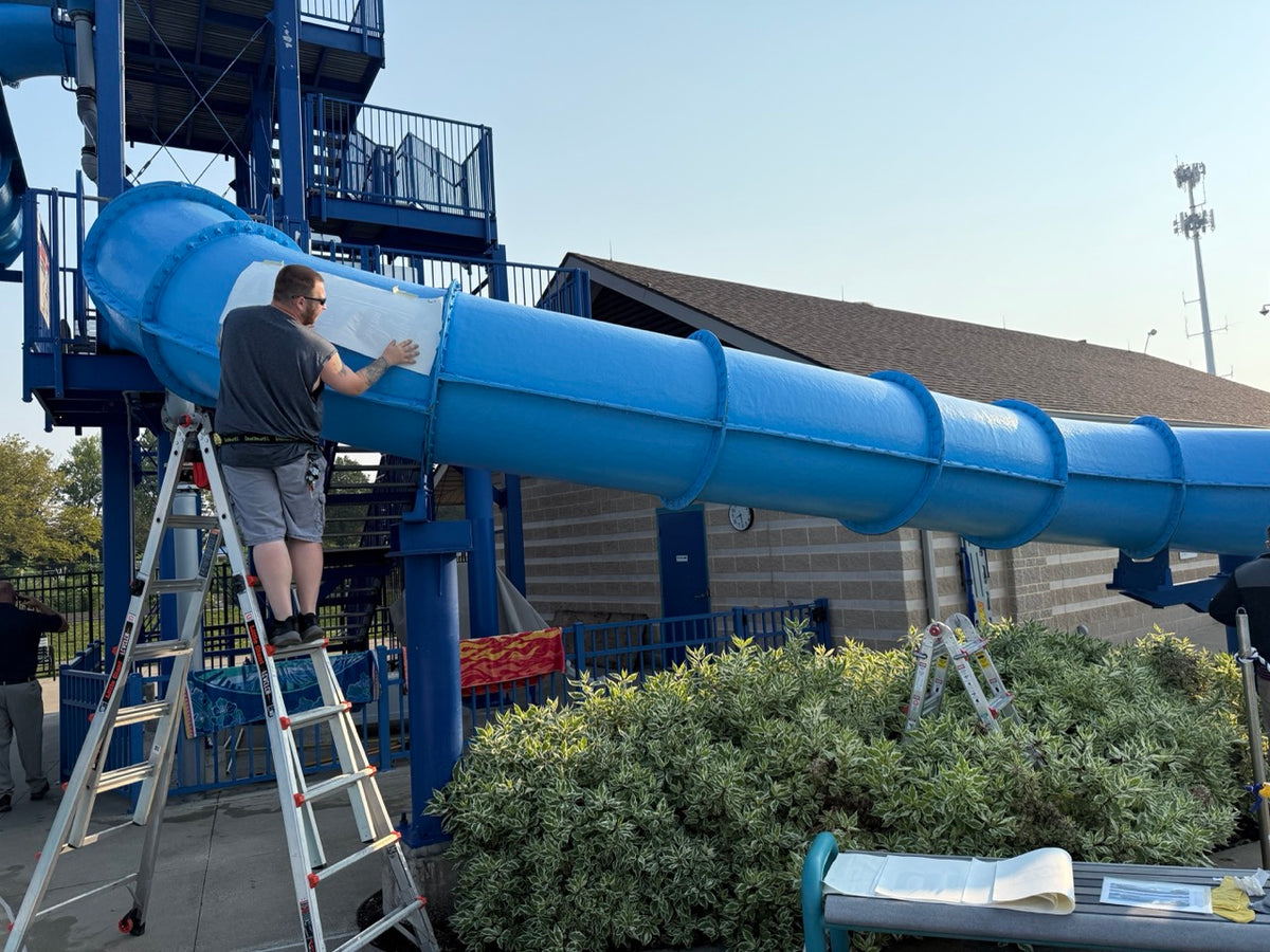 DG Creativ Installer applying vinyl graphics to a waterslide at Beachwood Aquatic Center in Beachwood, OH