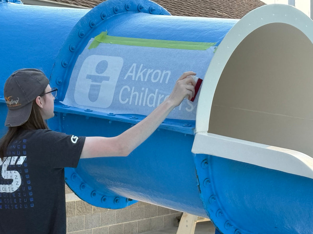 DG Creativ Installer applying vinyl graphics to a waterslide at Beachwood Aquatic Center in Beachwood, OH